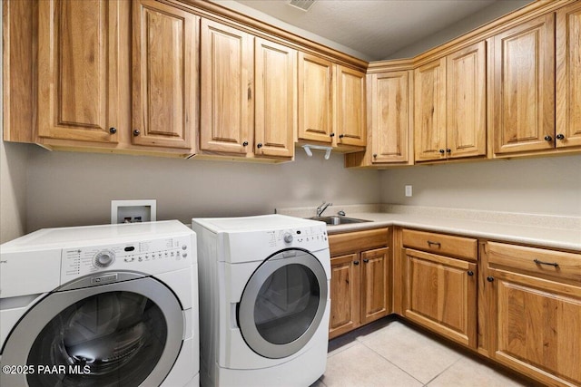 laundry area featuring a sink, light tile patterned flooring, cabinet space, and washing machine and clothes dryer