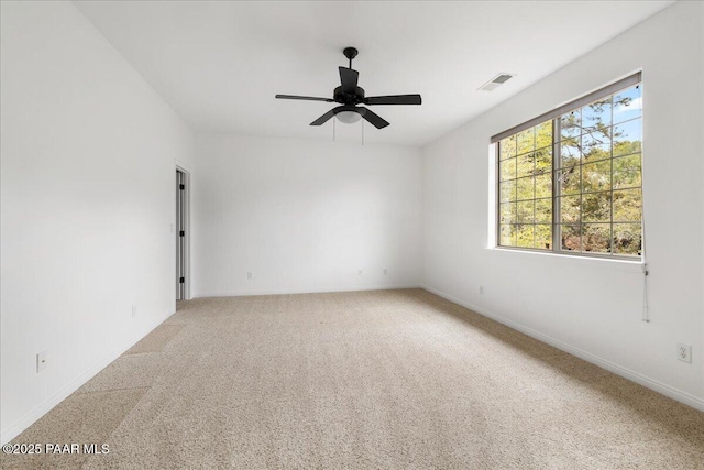 unfurnished room featuring visible vents, light colored carpet, baseboards, and a ceiling fan