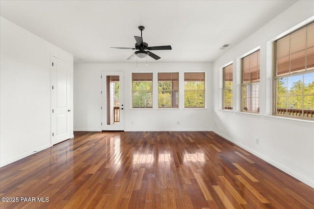 empty room featuring hardwood / wood-style floors, baseboards, visible vents, and ceiling fan