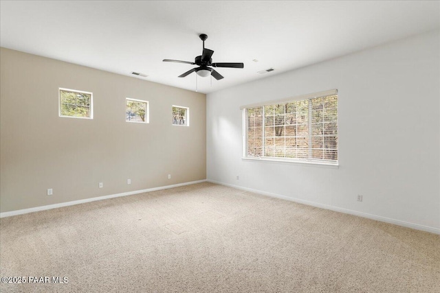 unfurnished room featuring light carpet, a healthy amount of sunlight, visible vents, and ceiling fan