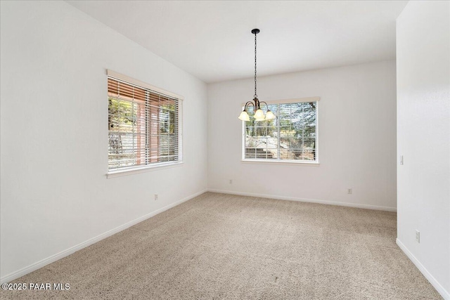 spare room featuring a chandelier, baseboards, and carpet