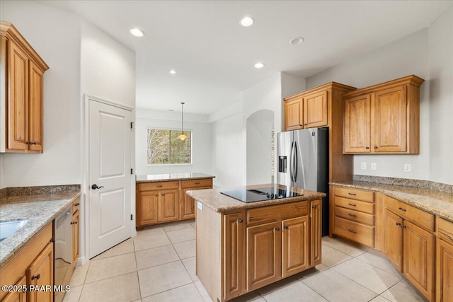 kitchen featuring a kitchen island, recessed lighting, arched walkways, appliances with stainless steel finishes, and light stone countertops