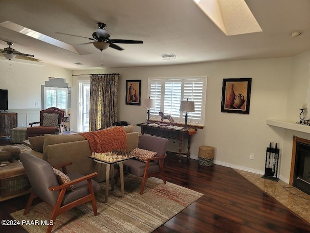 living room with ceiling fan, dark wood-type flooring, and a skylight