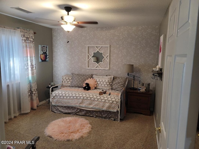 bedroom featuring ceiling fan, light colored carpet, and a textured ceiling