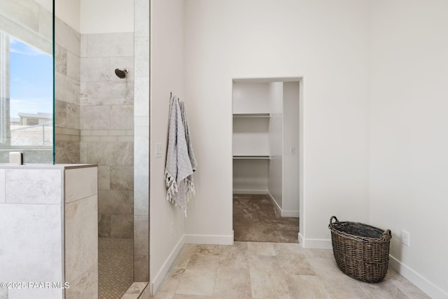 full bath featuring a walk in closet, baseboards, and a walk in shower