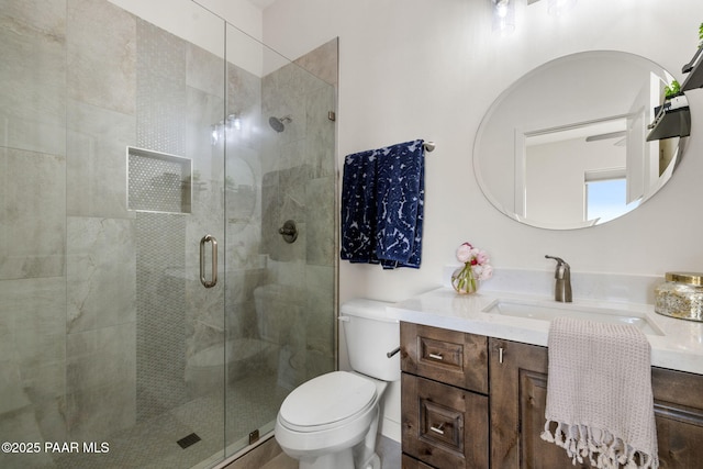 full bathroom featuring toilet, a stall shower, and vanity