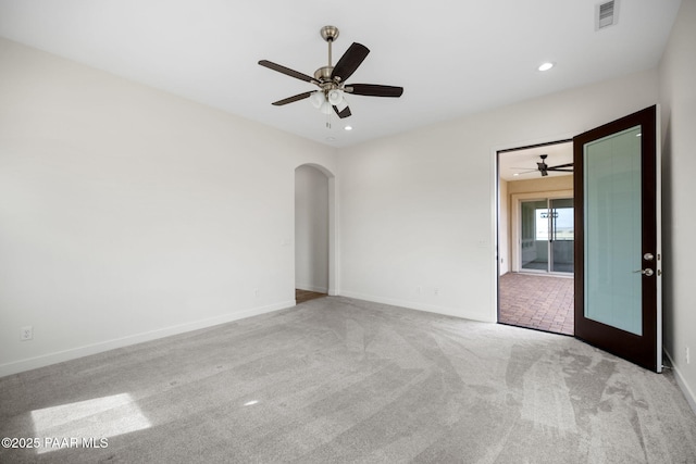 carpeted spare room with baseboards, visible vents, arched walkways, ceiling fan, and recessed lighting