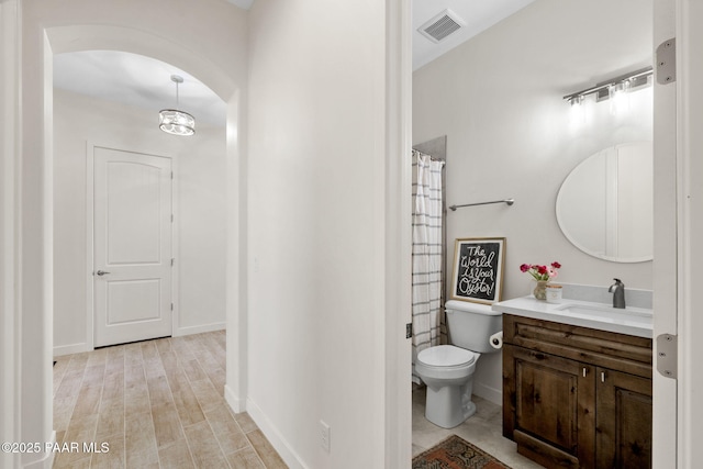 bathroom featuring toilet, vanity, wood finished floors, baseboards, and visible vents