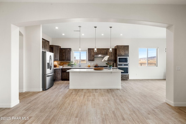 kitchen with dark brown cabinets, light countertops, plenty of natural light, and stainless steel appliances
