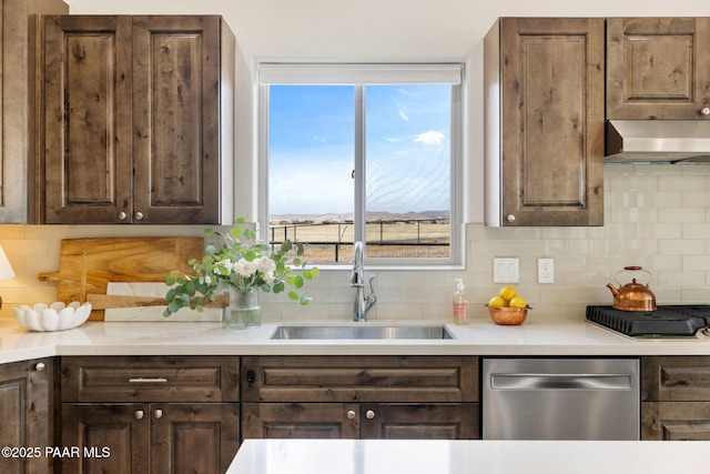kitchen featuring decorative backsplash, dishwasher, dark brown cabinetry, under cabinet range hood, and a sink