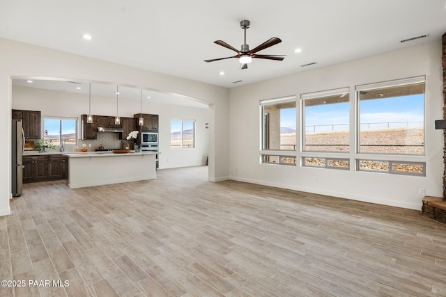 unfurnished living room with a ceiling fan, visible vents, light wood-style floors, and recessed lighting