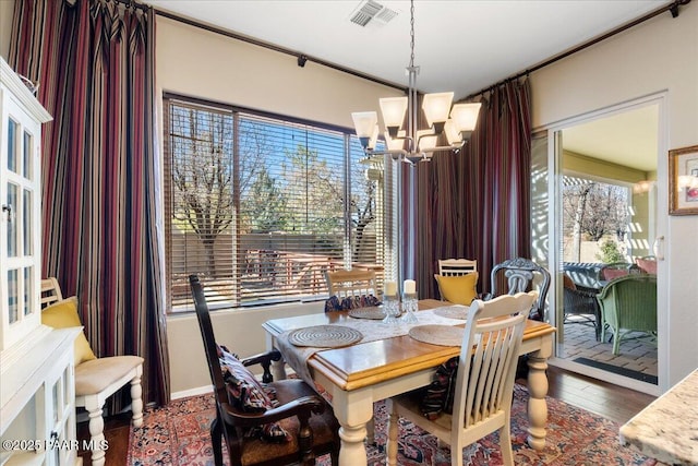 dining space with dark wood-type flooring and a chandelier