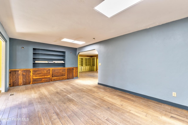 769 Cherokee Rd, Prescott, AZ 86303 - unfurnished living room featuring arched walkways, built in shelves, and hardwood / wood-style floors