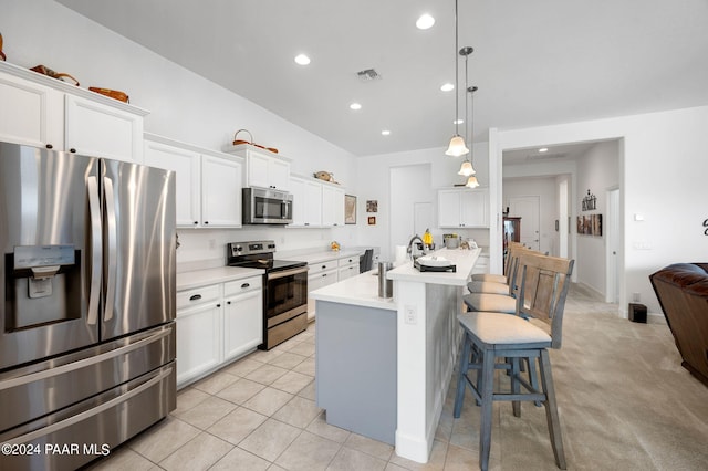 kitchen with white cabinetry, a kitchen island with sink, hanging light fixtures, and stainless steel appliances