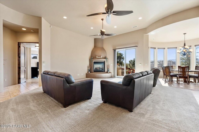 living room featuring ceiling fan with notable chandelier, light tile patterned floors, and a fireplace