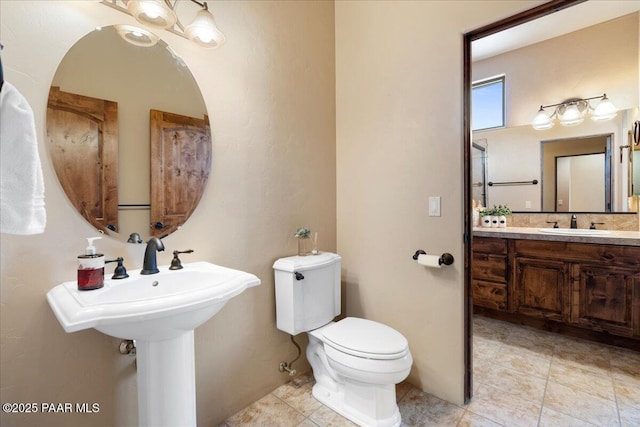 bathroom with toilet and dual sinks