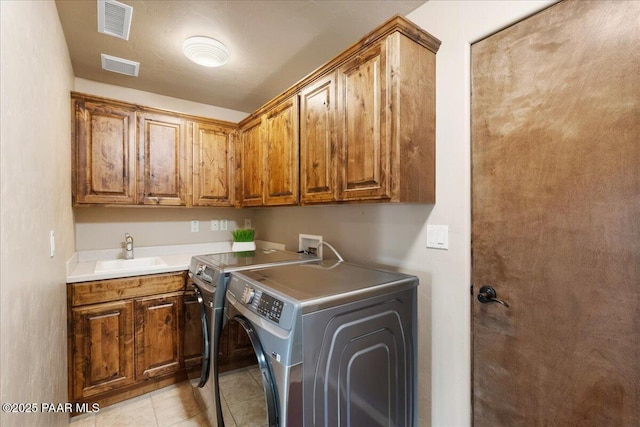 laundry room with cabinets, light tile patterned floors, washer and dryer, and sink