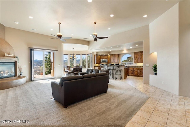 living room featuring ceiling fan with notable chandelier, light tile patterned floors, and lofted ceiling