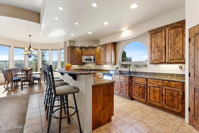 kitchen featuring a center island, stainless steel appliances, an inviting chandelier, dark stone counters, and decorative light fixtures