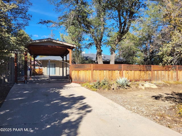 exterior space featuring a fenced front yard, driveway, a detached carport, and a gate