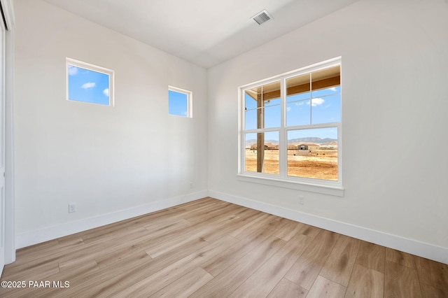 spare room featuring baseboards, visible vents, and light wood-style floors