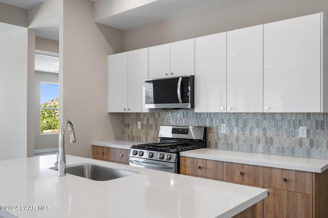 kitchen featuring backsplash, white cabinetry, sink, and appliances with stainless steel finishes