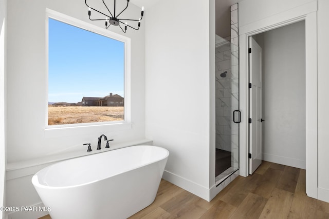 bathroom with plus walk in shower, hardwood / wood-style floors, and an inviting chandelier