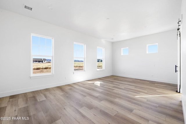 spare room featuring light hardwood / wood-style floors and a barn door