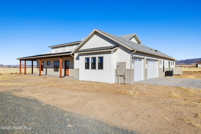 view of front of home featuring a garage, central AC unit, and covered porch