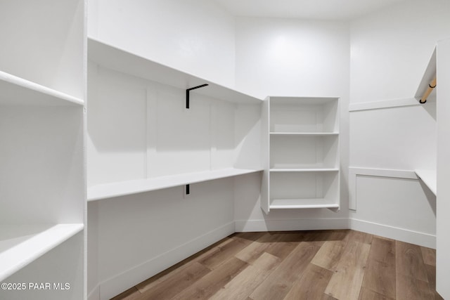 walk in closet with light hardwood / wood-style flooring