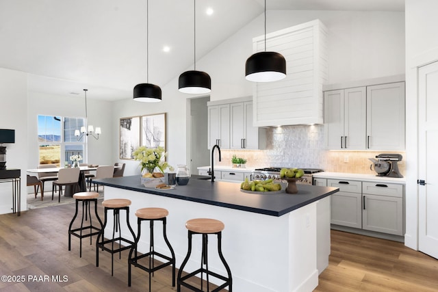 kitchen featuring a kitchen island with sink, hanging light fixtures, and range