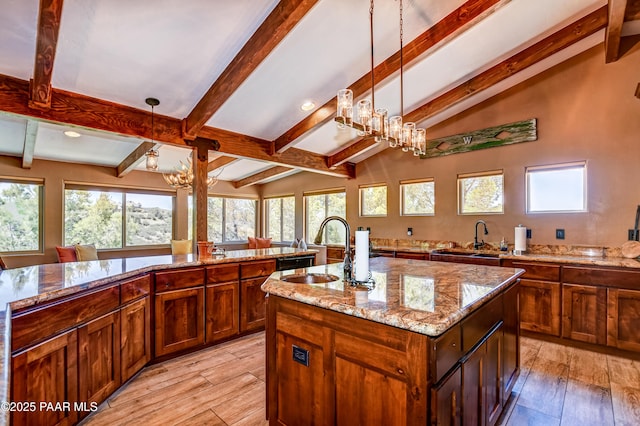 kitchen featuring sink, a chandelier, hanging light fixtures, a kitchen island with sink, and a healthy amount of sunlight