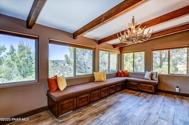 sunroom / solarium featuring beam ceiling and a chandelier