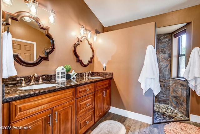 bathroom with hardwood / wood-style flooring, tiled shower, and vanity