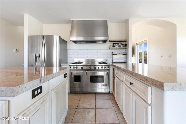 1310 W Carlock Dr, Prescott, AZ 86305 - kitchen featuring wall chimney range hood, stainless steel appliances, tasteful backsplash, light stone countertops, and light tile patterned flooring