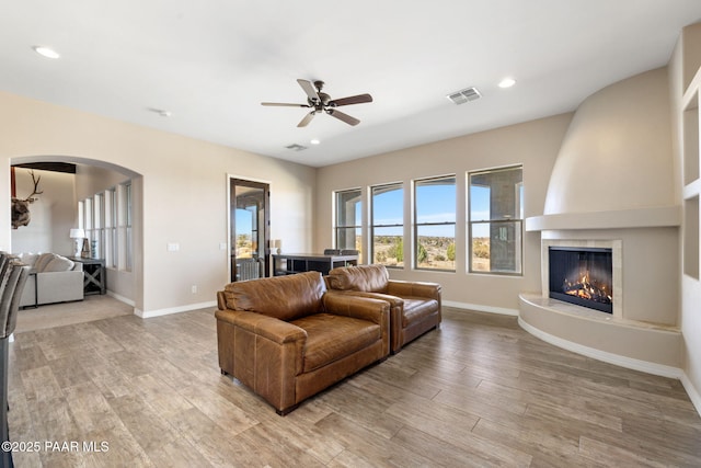 12300 W Slate Rd, Prescott, AZ 86305 - living room with arched walkways, visible vents, light wood-type flooring, and a ceiling fan