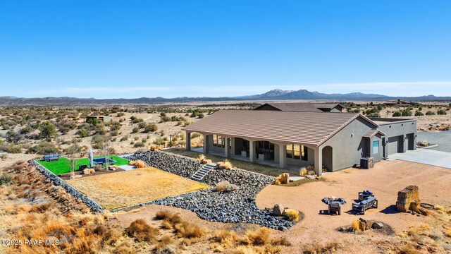 12300 W Slate Rd, Prescott, AZ 86305 - rear view of property with stucco siding, a tile roof, a mountain view, concrete driveway, and a garage