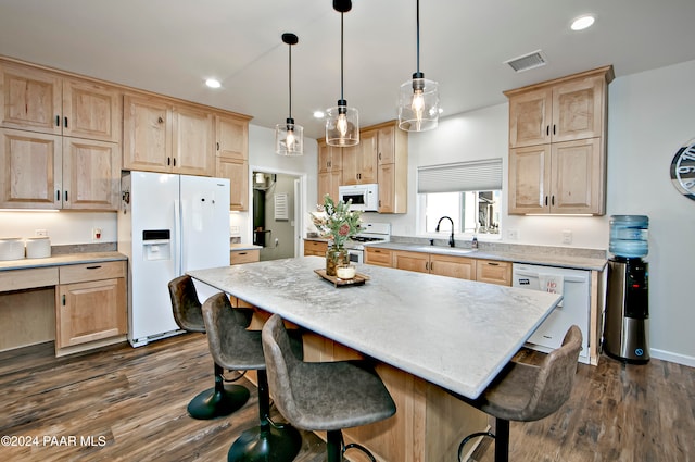 kitchen featuring pendant lighting, white appliances, sink, a kitchen island, and dark hardwood / wood-style flooring