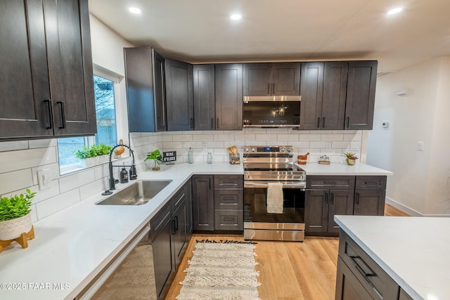 kitchen with stainless steel electric range oven, recessed lighting, a sink, decorative backsplash, and light wood-style floors