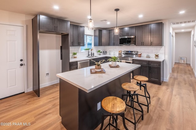 kitchen with light wood finished floors, visible vents, a kitchen breakfast bar, and stainless steel appliances