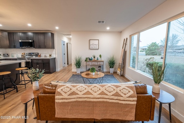 living area with recessed lighting, visible vents, and light wood finished floors