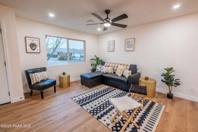 living room featuring baseboards, light wood-style floors, visible vents, and ceiling fan