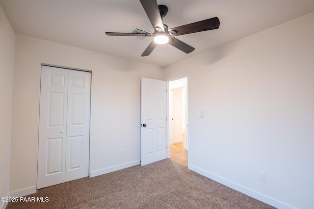 unfurnished bedroom with a closet, carpet flooring, a ceiling fan, and baseboards