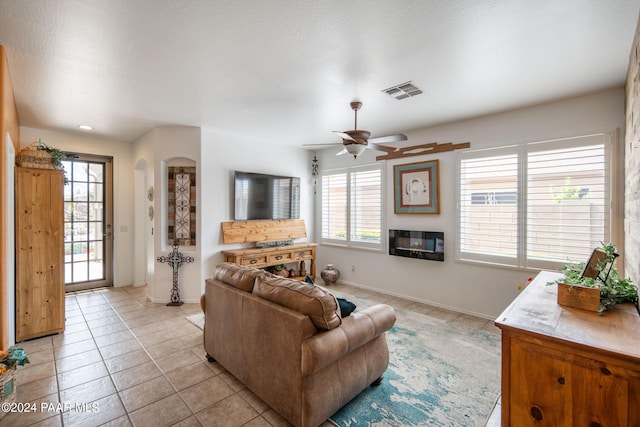 living room featuring a fireplace, light tile patterned floors, a textured ceiling, and ceiling fan