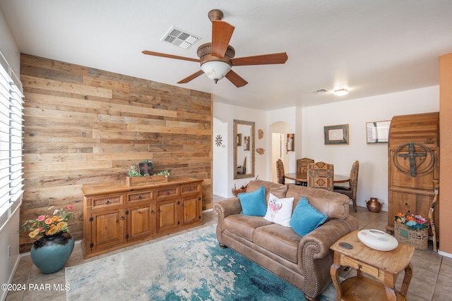 living room with ceiling fan and wood walls