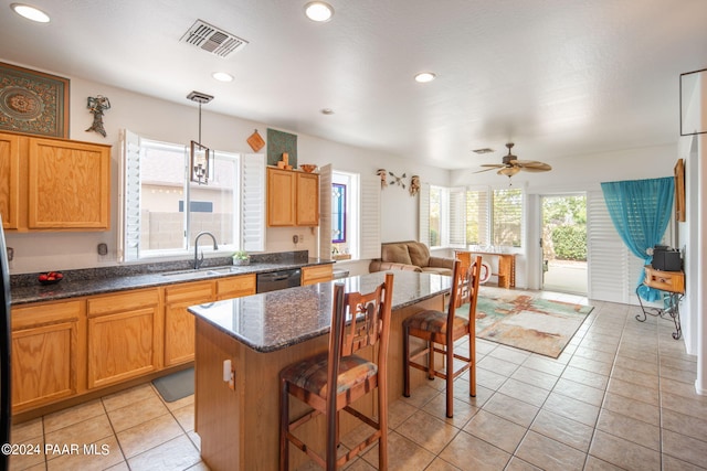 kitchen with a kitchen breakfast bar, ceiling fan, sink, a center island, and hanging light fixtures