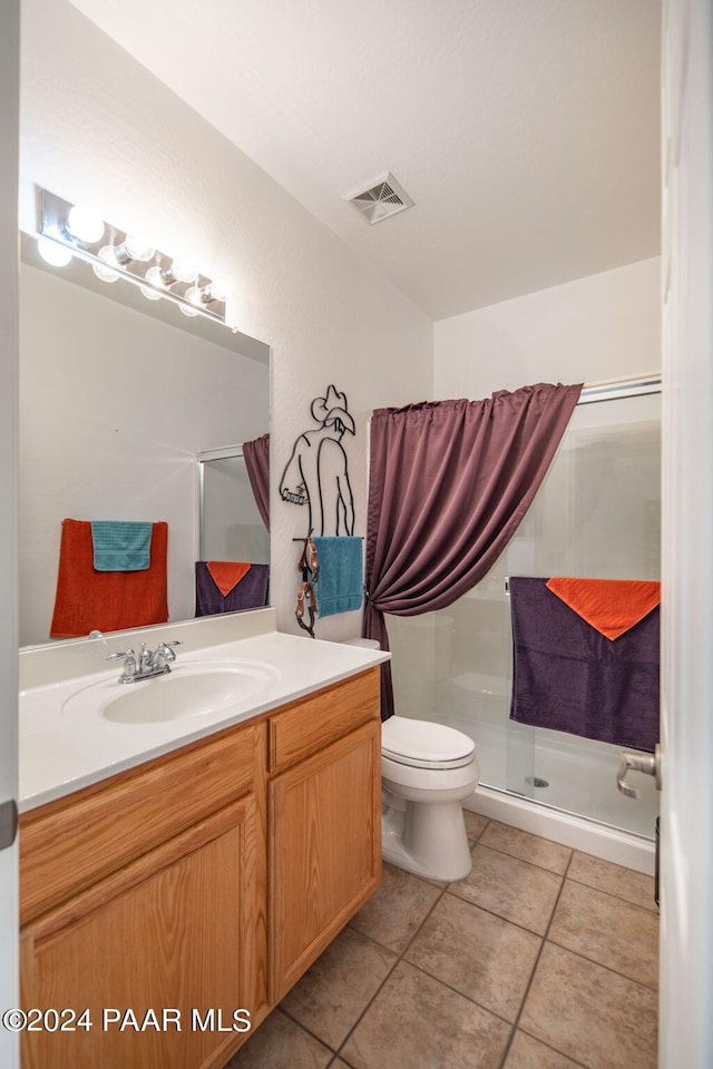 bathroom featuring toilet, vanity, tile patterned floors, and an enclosed shower