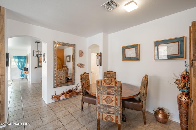 dining space featuring light tile patterned floors and a notable chandelier