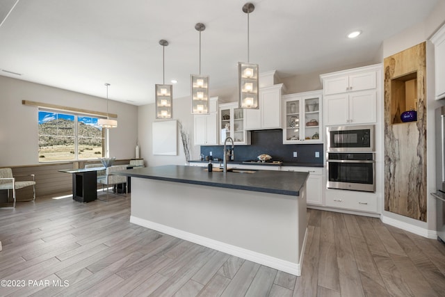 3771 Blazing Ore Trl, Prescott, AZ 86301 - kitchen featuring hanging light fixtures, stainless steel appliances, a center island with sink, white cabinets, and light wood-type flooring