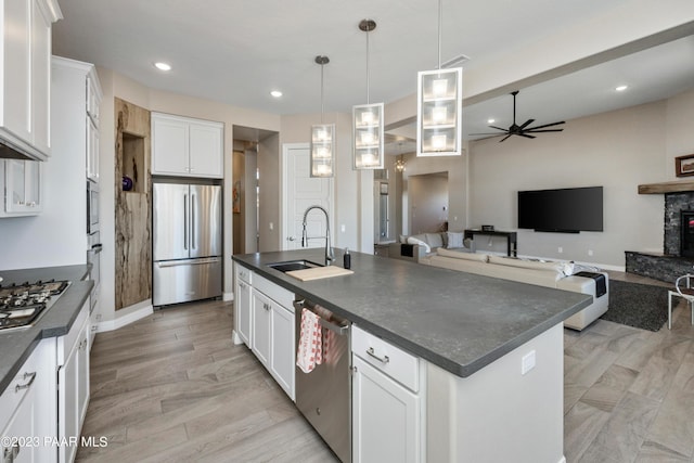 3771 Blazing Ore Trl, Prescott, AZ 86301 - kitchen with white cabinetry, sink, stainless steel appliances, a fireplace, and a center island with sink